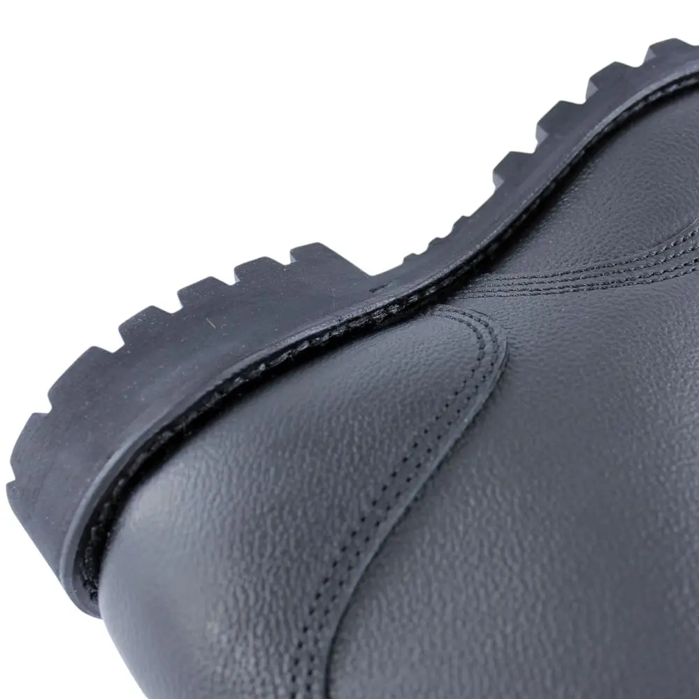 Gros plan d’une chaussure militaire en cuir bleu foncé avec semelle crantée robuste et surpiqûres visibles.