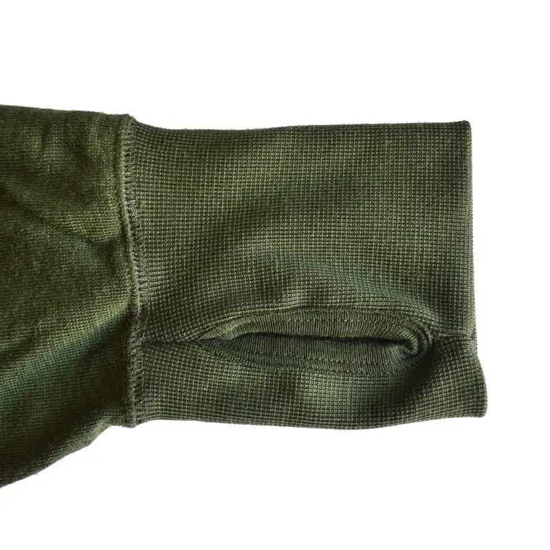 Poignet d'un vêtement militaire en tissu kaki vert olive, manche tour, fermeture cousue et texture côtelée.